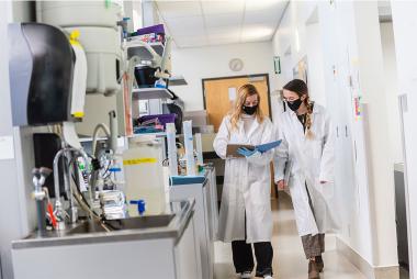 两个穿着白大褂的女人在实验室环境中走在一起